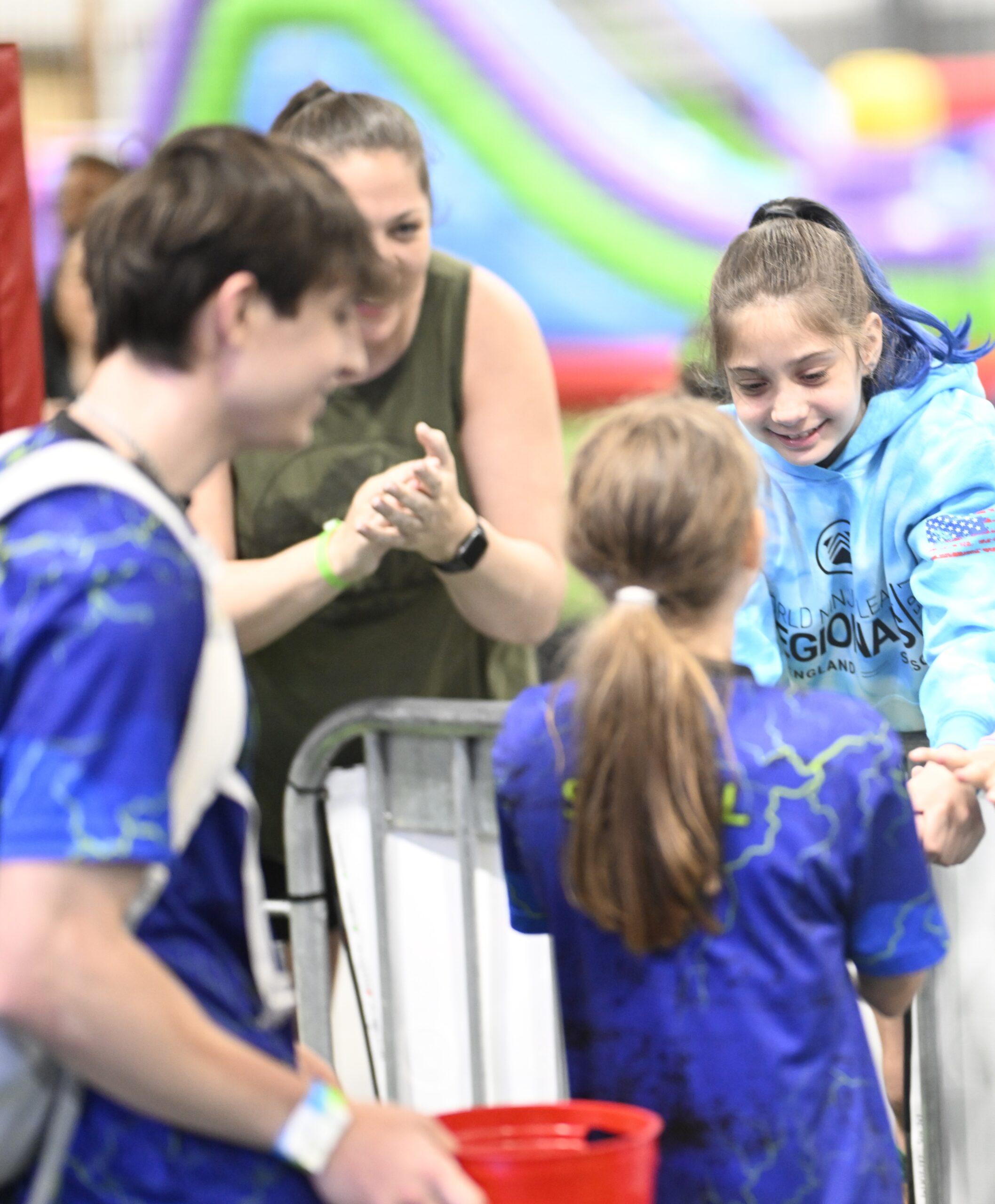 A young female ninja athlete smiles and congratulates another athlete after completing a ninja course.